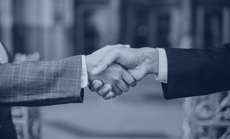Aperto de mãos entre dois executivos formalizando uma parceria