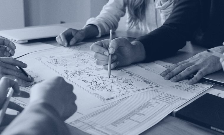 Profissionais analisando um projeto técnico sobre a mesa
